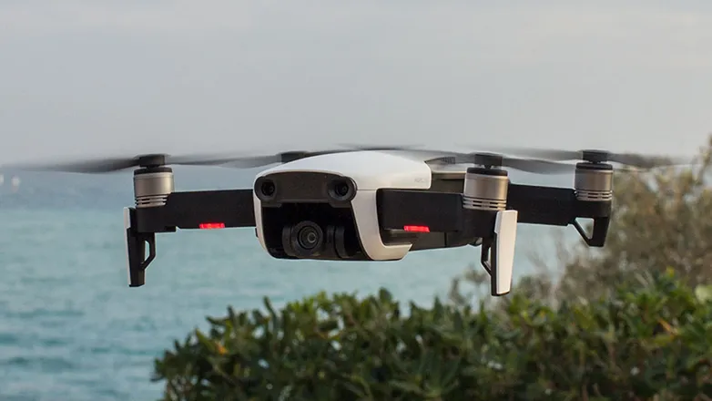 Bir drone havada uçuyor arkasında deniz manzarası var