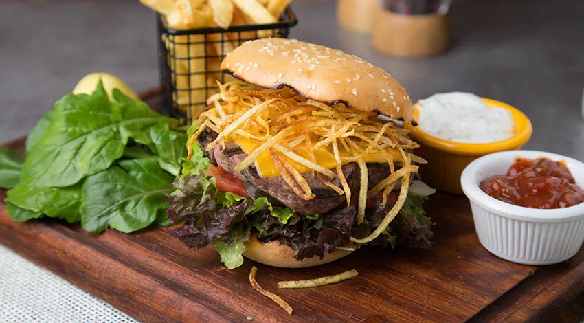 İçinde çok ince kesilmiş kızarmış patates olan kocaman bir hamburger
