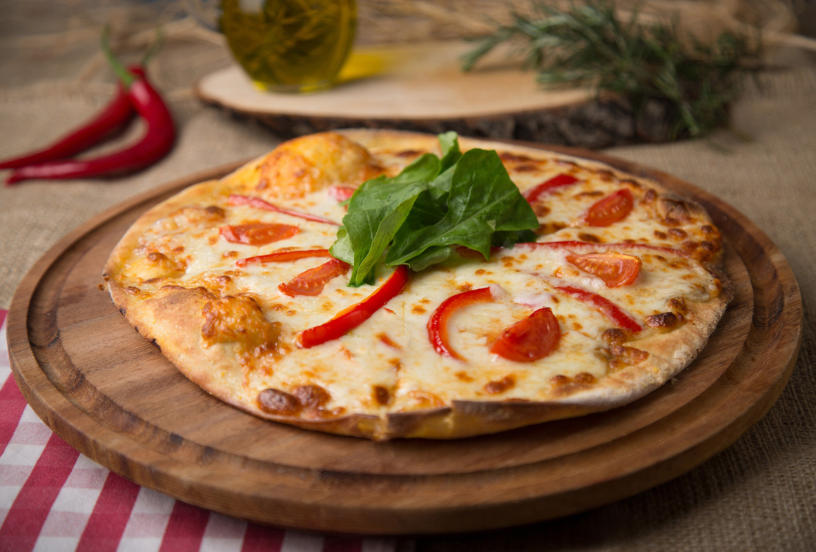 Üzerinde domates dilimleri ve kırmızı biber olan klasik pizza.