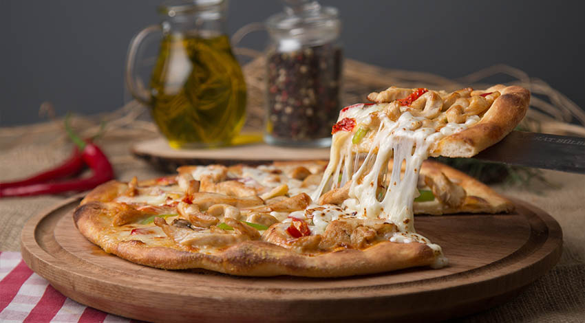 Pizza dilimini alırken uzayan peynir, ahşap sunum tahtasında servis edilmiş