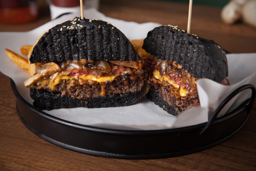 Siyah burger ekmeğinden yapılmış burger, ortadan ikiye kesilip ızgara edilmiş.