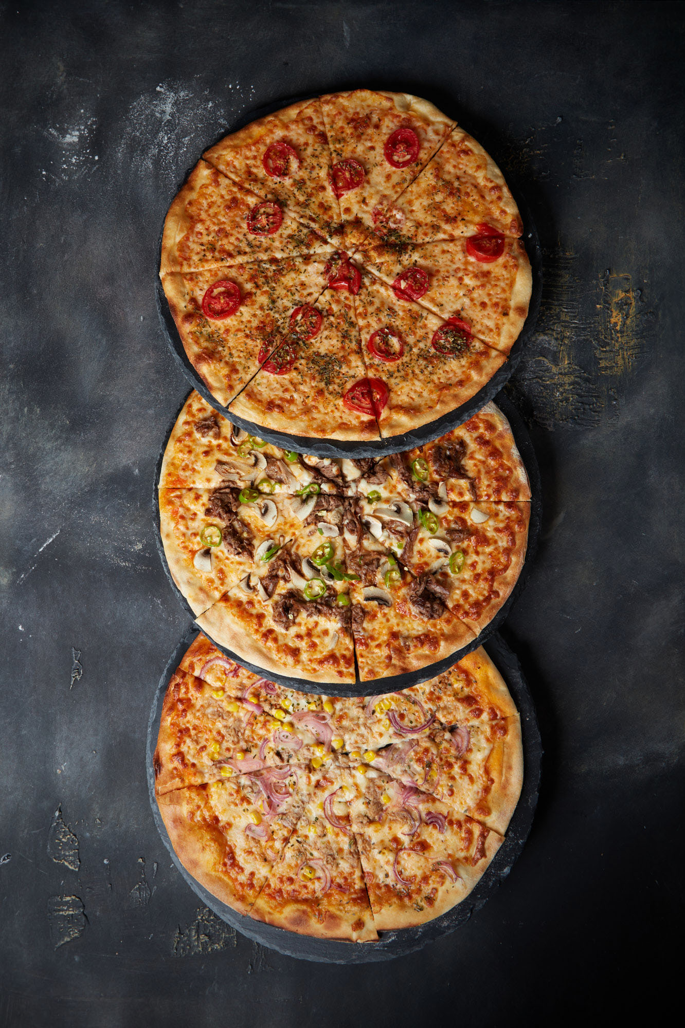 Üç pizza alt alta duruyor üstten çekilmiş bir fotoğraf.